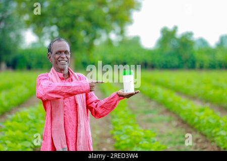 Indiano Happy Farmer tenendo in mano bottiglia vuota, Happy Farmer che mostra bottiglia bianca Foto Stock