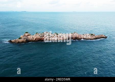 vista dall'alto da un drone. bella isola rocciosa solitaria nel mare con le onde. Bellissima isola rocciosa sul cielo blu Foto Stock