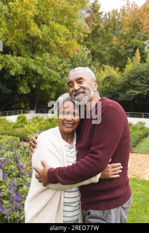 Ritratto di una felice coppia birazziale anziana che abbraccia in giardino a casa, spazio fotocopie Foto Stock