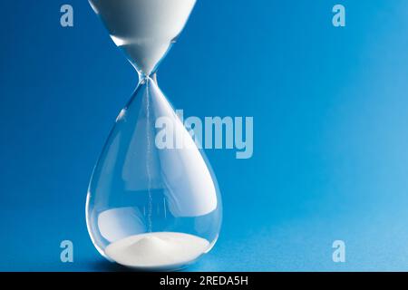 Primo piano della clessidra con sabbia bianca e spazio copia su sfondo blu Foto Stock