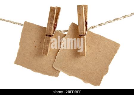 Due fogli di carta artigianale attaccati a una corda con clothespins isolati su sfondo bianco Foto Stock