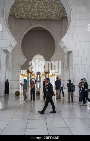 Abu Dhabi, Emirati Arabi Uniti - 17 aprile 2023. Una foto verticale che include i turisti all'interno della grande Moschea di Abu Dhabi. Foto Stock