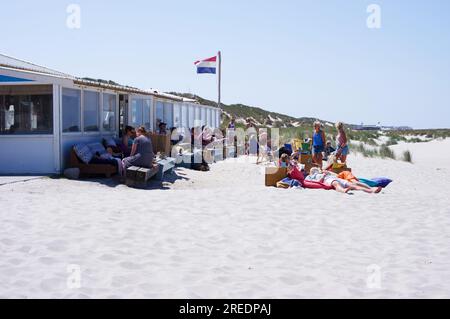 Terschelling, Paesi Bassi - 16 giugno 2023: Le persone si rilassano in una terrazza di fronte a una tenda sulla spiaggia nella sabbia Foto Stock