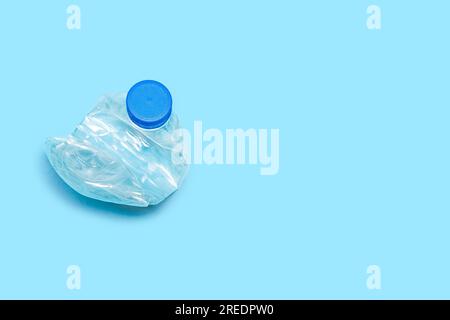 Una bottiglia usata per il riciclaggio di plastica PET. Design piatto per riciclaggio di bottiglie in plastica sfondo blu. Bottiglia singola schiacciata spazzatura in plastica Foto Stock