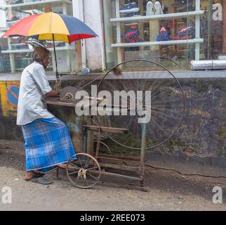 Sri Lanka, Kandy - 13 gennaio 2020: Macinacaffè per coltelli da strada con la sua affilatrice fatta in casa: Il dispositivo è azionato da un pedale e dalla dinamica Foto Stock