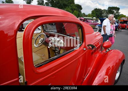I visitatori di una mostra di auto d'epoca e personalizzate americane passeranno davanti a un'automobile Packard personalizzata del 1937 Foto Stock