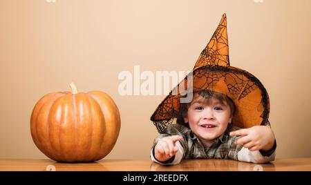 Bambino sorridente in cappello da strega con zucca di halloween. Trick o dolcetto. Ragazzino con zucca. Preparazione per Halloween. Buon Halloween Foto Stock