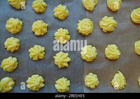 Cucina sveva, preparazione di mini sfoglie di panna, pasta choux cruda spruzzata su carta da forno, eclairs, profiteroles, pasticceria in scatola, torte da forno, choux Foto Stock