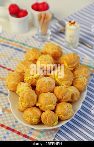 Cucina sveva, mini bocconcini di crema ripieni di formaggio cremoso di capra, eclairs di formaggio cremoso, profiterole su piatto da portata, frollino, forno Foto Stock