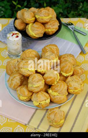 Cucina sveva, mini bocconcini di crema ripieni di formaggio cremoso di capra, eclairs di formaggio cremoso, profiterole su piatto, frollino, torte da forno Foto Stock