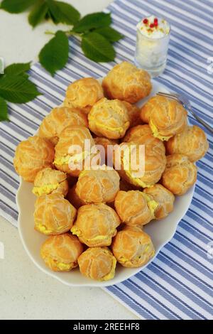 Cucina sveva, mini bocconcini di crema ripieni di formaggio cremoso di capra, eclairs di formaggio cremoso, profiterole su piatto da portata, frollino, forno Foto Stock