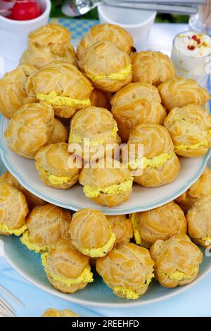 Cucina sveva, mini bocconcini di crema ripieni di formaggio cremoso di capra, eclairs di formaggio cremoso, profiterole su piatto, frollino, torte da forno Foto Stock