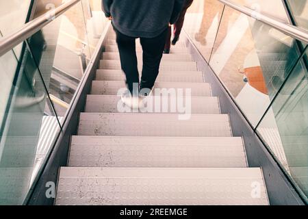 Le gambe sfocate di una persona scendono da una scala Foto Stock