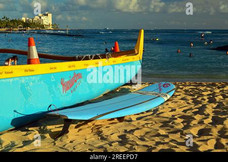 Una canoa e una tavola da surf, due popolari modi di trasporto alle Hawaii, si trovano sulla sabbia di Waikiki Beach Foto Stock