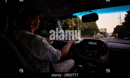 Donna adulta matura sorridente mentre guida un'auto Foto Stock