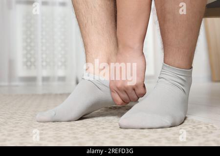 Uomo che indossa calzini leggeri a casa, primo piano Foto Stock