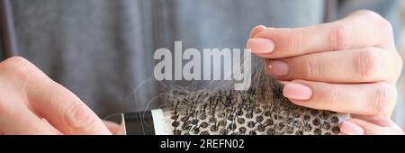 Le mani delle donne tengono il pettine con molti capelli caduti. Foto Stock