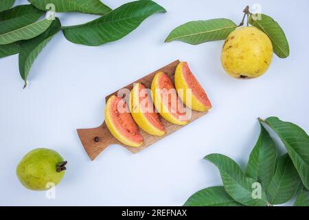fette di guava fresche con foglie verdi su sfondo bianco Foto Stock