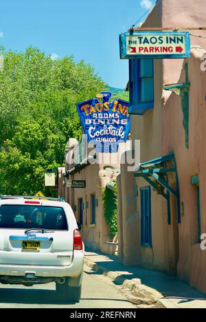 Taos, New Mexico, USA - 24 luglio 2023: Un veicolo passa accanto all'insegna al neon d'epoca "Taos Inn" che pubblicizza la storica proprietà nei pressi di Taos Plaza. Foto Stock