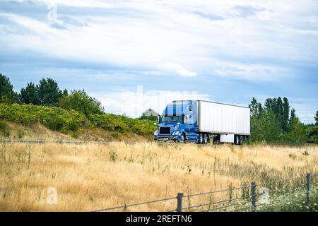 Trattore semirimorchio per trasporto lungo con carro di perforazione grande blu di grado industriale con cabina alta per il riposo del conducente del veicolo che trasporta carichi commerciali in semirimorchi per furgoni asciutti Foto Stock