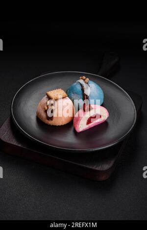 Deliziosi dolci e colorati dessert mochi o gelato con impasto di riso e condimenti su uno sfondo di cemento scuro Foto Stock