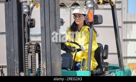 Lavoratrice lavoratrice in Hard Hat guida il caricatore nel cantiere della fabbrica di rifiuti Foto Stock