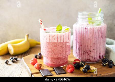 Lamponi, banane e ribes nero. Set di deliziosi frullati freschi o frullati con frutti di bosco freschi. Copia spazio. Foto Stock