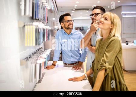 Il consulente di vendita consiglia le persone che scelgono nuovi dispositivi digitali nei punti vendita. Consulenza professionale Foto Stock