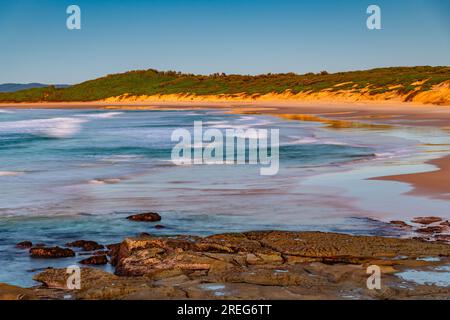 Paesaggio marino al sorgere del sole con un basso banco di nuvole a Soldiers Beach, situato a Norah Head, sulla costa centrale del New South Wales, Australia. Foto Stock