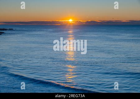 Paesaggio marino al sorgere del sole con un basso banco di nuvole a Soldiers Beach, situato a Norah Head, sulla costa centrale del New South Wales, Australia. Foto Stock