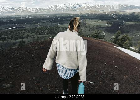 la donna con una bottiglia d'acqua cammina lungo un crinale in cima a un'escursione Foto Stock