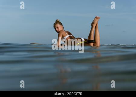 Donna surfista su un'onda. Donna felice che giace sulla tavola da surf Foto Stock