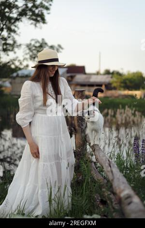 Giovane donna in abito e cappello in un campo di lupino, in stile rustico, Foto Stock