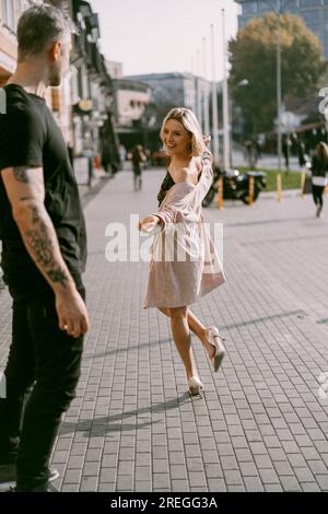 L'uomo su uno skateboard incontra una donna per strada. Coppia innamorata. Foto Stock