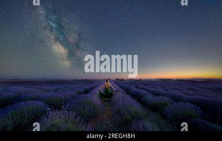 donna al crepuscolo in un cielo di strega di lavanda con via lattiginosa Foto Stock