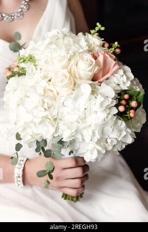 Bouquet nuziale bianco e pesca tenuto dalla sposa Foto Stock