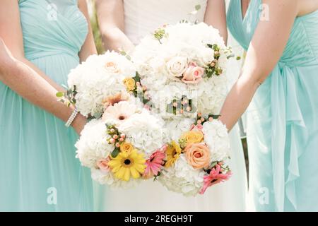 Mazzi da sposa floreali tenuti da una festa nuziale in abiti ottanio Foto Stock