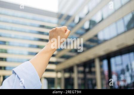 Vista ravvicinata dal basso della mano femminile alzata un pollice il pugno simbolo rappresenta la lotta Foto Stock