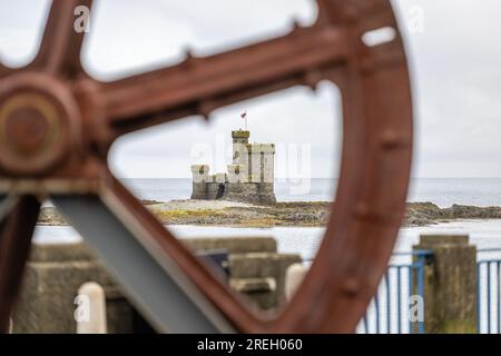 Il Castello di Rifugio sull'Isola di St Mary, il porto di Douglas Bay, l'Isola di Man, visto attraverso la vecchia ruota di ferro recuperata dalla funivia Foto Stock
