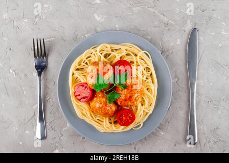 Pasta e polpette piccanti stufate in salsa di pomodoro, servite su piatto grigio su sfondo grigio Foto Stock