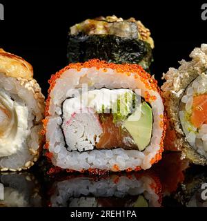 Sushi rotoli di diversi tipi su sfondo nero con riflessi Foto Stock