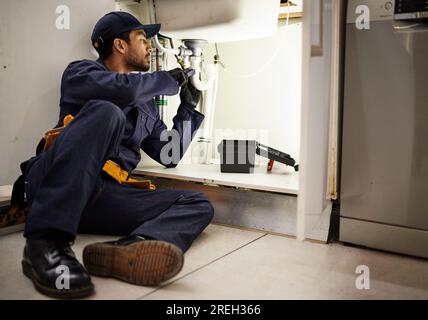 Idraulica, tuttofare e manutenzione con uomo in cucina per riparazione, industriale e ispezione. Tubi, utensili e sicurezza con lavello di fissaggio per idraulici maschio Foto Stock