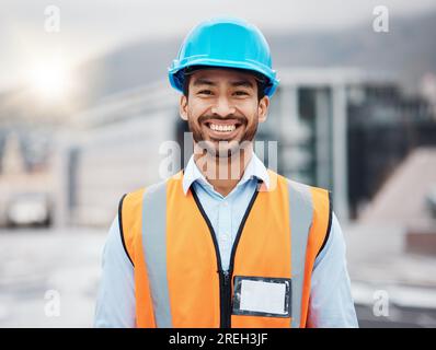 Felice uomo asiatico, architetto e ritratto in città per la costruzione, l'installazione o l'ispezione sul tetto. Un uomo, un ingegnere o un appaltatore sorride per Foto Stock