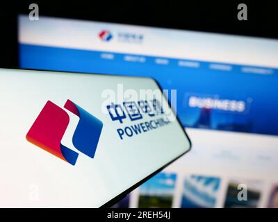 Cellulare con logo della società energetica cinese PowerChina sullo schermo di fronte al sito Web aziendale. Mettere a fuoco sul lato sinistro del display del telefono. Foto Stock