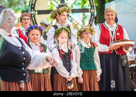 Gruppo di adulti e bambini in abiti tradizionali che suonano e cantano sul palco durante il XXVII Festival della canzone lettone in tutta la nazione e il XVII Festival della danza Foto Stock