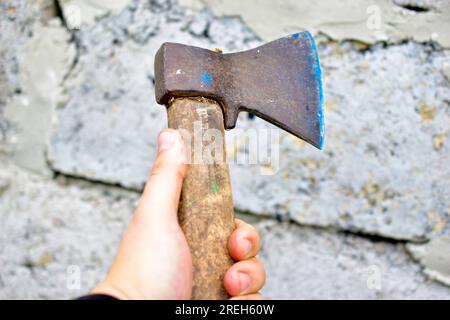 Un'ascia nelle mani di un uomo contro il muro Foto Stock