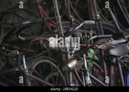 Pile di biciclette arrugginite d'epoca in officina Foto Stock