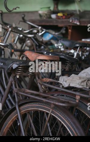 Pile di biciclette arrugginite d'epoca in officina Foto Stock