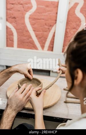 Romantica coppia di artigiani che modellano terracotta in argilla su tavola di legno in uno studio di ceramica Foto Stock