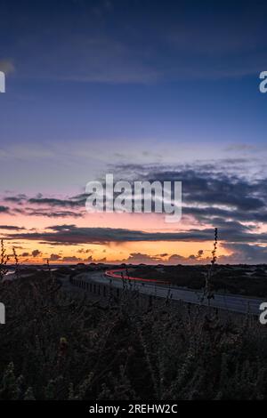 Bella mattinata su una strada tra le dune. Il sole sorge su una strada con le nuvole. Parco nazionale di Corralejo, Isole Canarie, Spagna Foto Stock